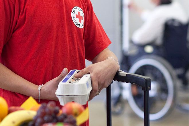 Foto: Ein DRK-Mitarbeiter hält eine Schachtel mit 10 frischen Eiern in den Händen. Vor ihm steht ein Obstkorb mit frischen Früchten.